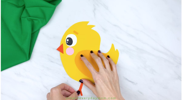Hands gluing feet onto handprint chick craft 