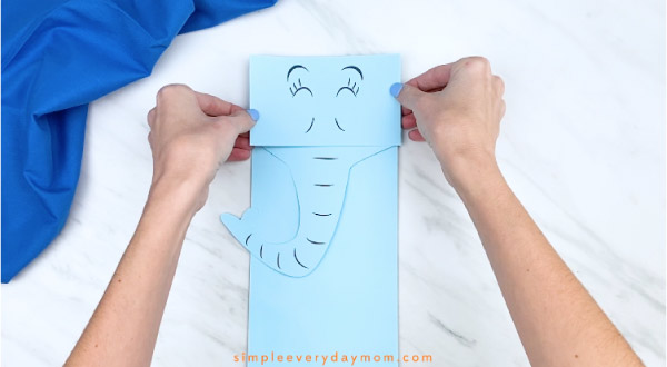 Hands gluing Horton face to paper bag 