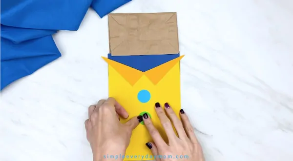 hands gluing buttons onto paper Pete the Cat puppet