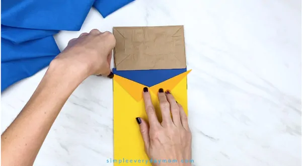 hands gluing collar onto paper bag Pete the Cat