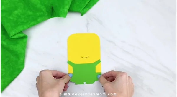 Hands gluing green overall to paper minion 