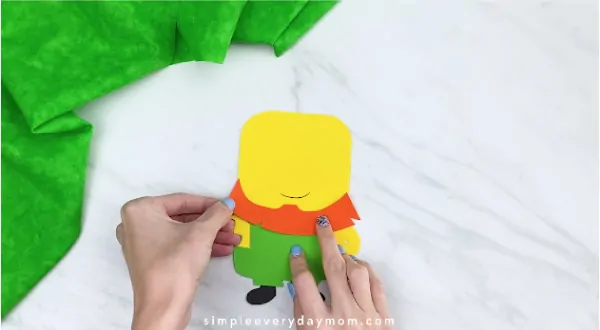 Hands gluing beard onto leprechaun minion craft 