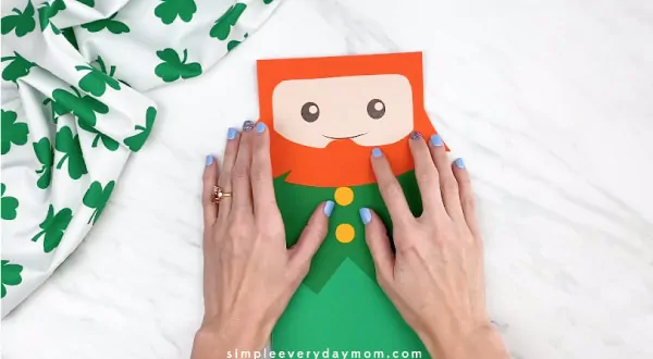 Hands gluing beard onto paper bag leprechaun craft 
