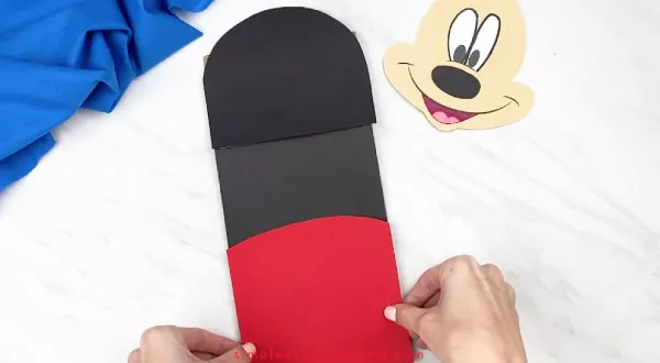 hands gluing mickey pants onto paper bag