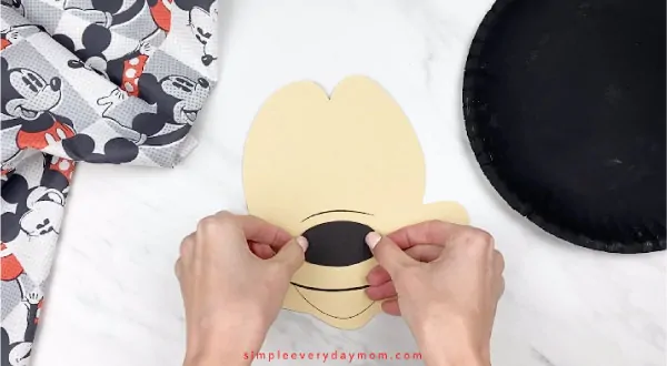 hands gluing paper nose onto Mickey\'s face