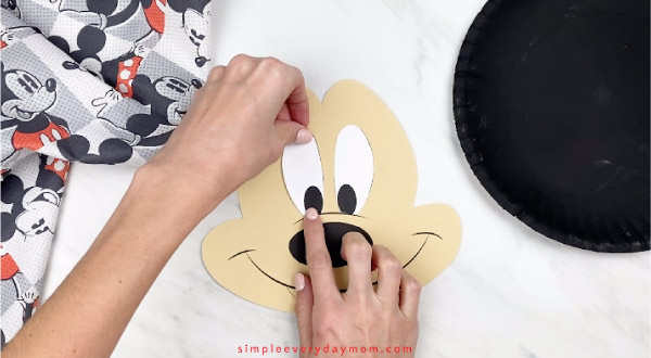 hands gluing paper eyes onto Mickey face
