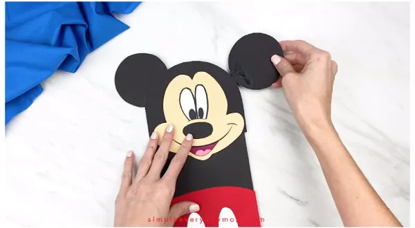 hands gluing mickey ears onto mickey mouse craft