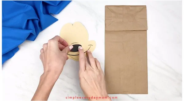 hands gluing nose onto paper mickey mouse craft