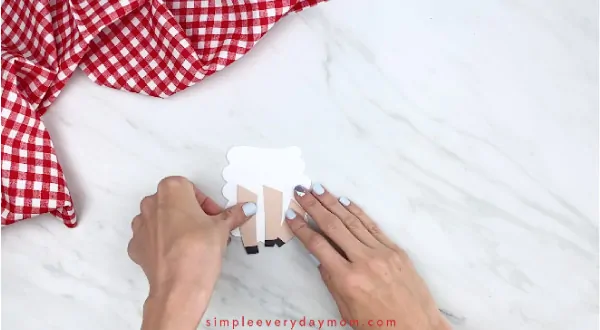 Hands gluing legs onto sheep card craft 