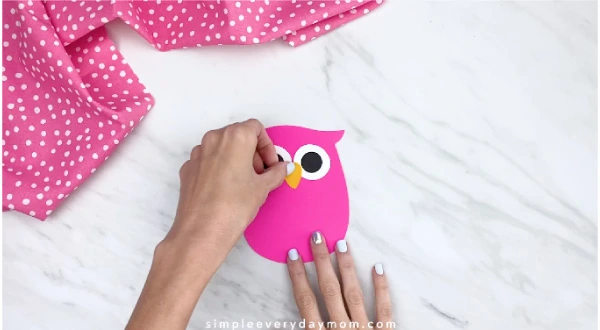 hand gluing beak onto pink paper owl