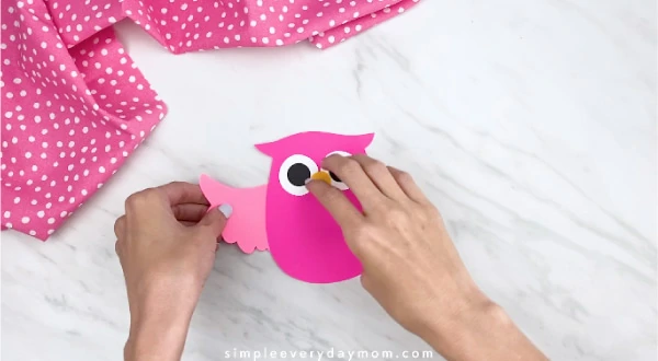 hands gluing on wing to pink paper owl 