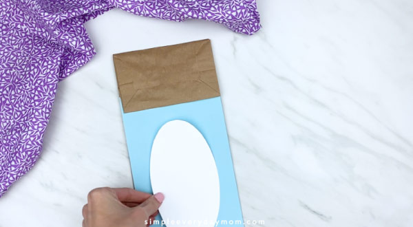Hands gluing belly onto paper bag bunny craft 