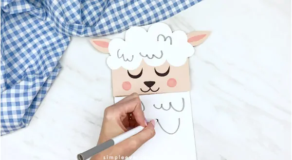 Hands drawing fluff lines onto paper bag sheep craft 