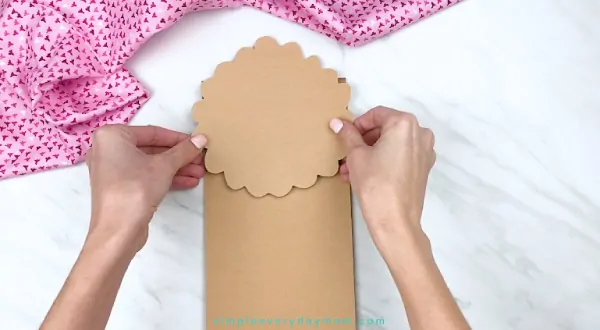hands gluing paper onto brown paper bag