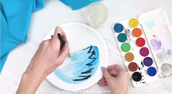 Hands painting water onto paper plate 