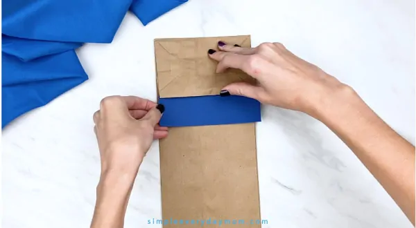 hands gluing blue onto paper bag Pete the Cat
