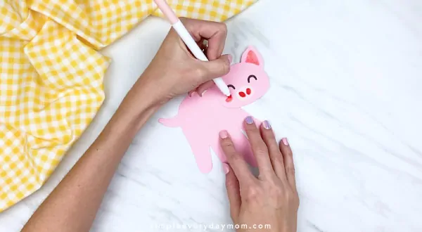 Hands drawing cheeks onto handprint pig 