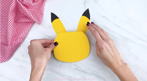 Hands gluing Pikachu ears to head 