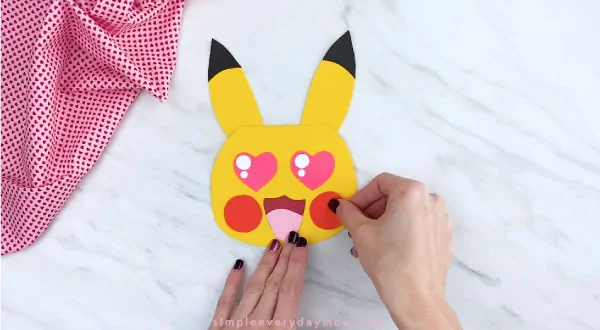 Hands gluing cheeks to Pikachu’s face 