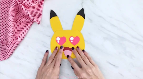 Hands gluing mouth onto Pikachu face 