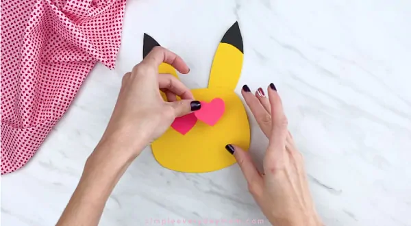 Hands gluing heart eyes to Pikachu face 