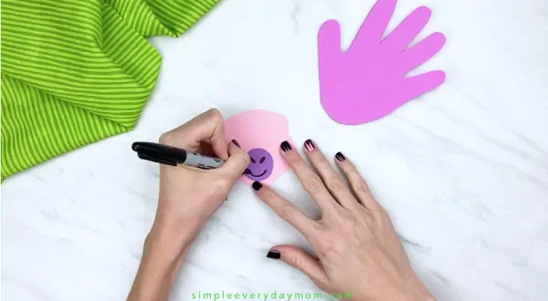 hands drawing nose and mouth on dinosaur craft