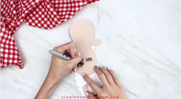 Hands writing message inside paper sheep card craft 