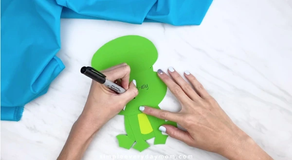 Hands writing message inside frog card craft 