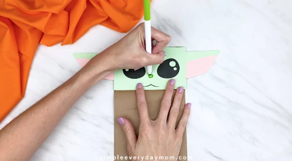 Hands drawing green nose on paper bag yoda face 