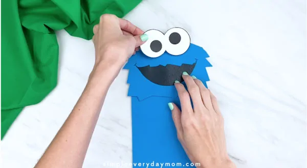 hand gluing on eyes to paper bag cookie monster craft