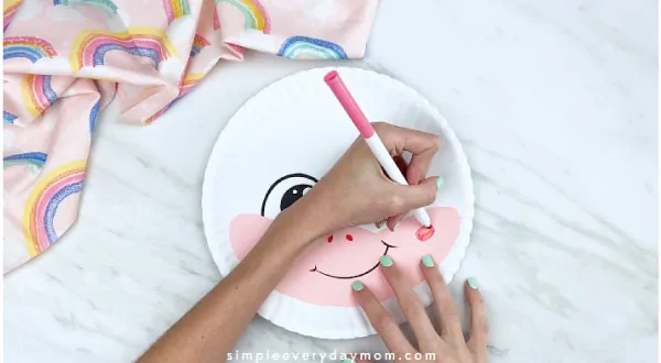 hands drawing on cheeks with pink marker 