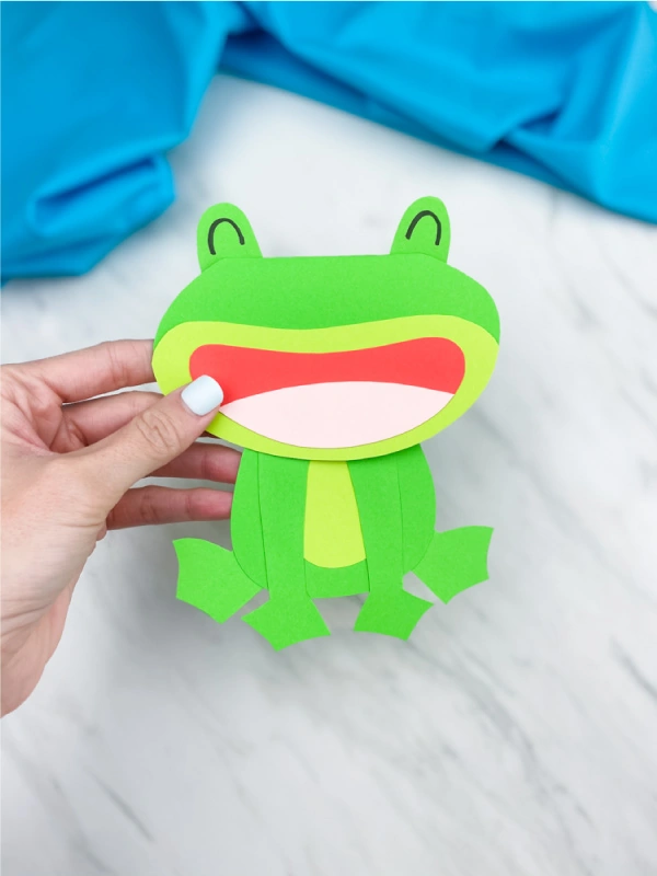 Hand holding paper frog card craft 