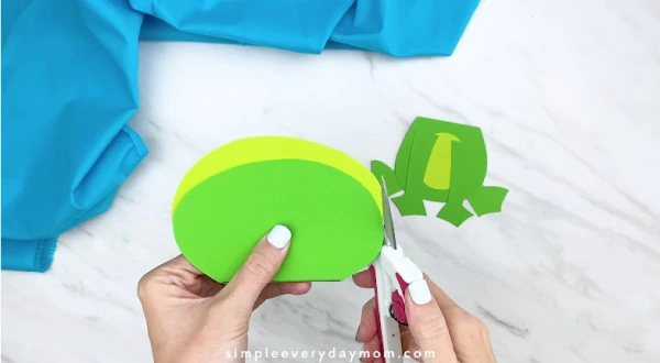 Hands trimming light green paper off 
