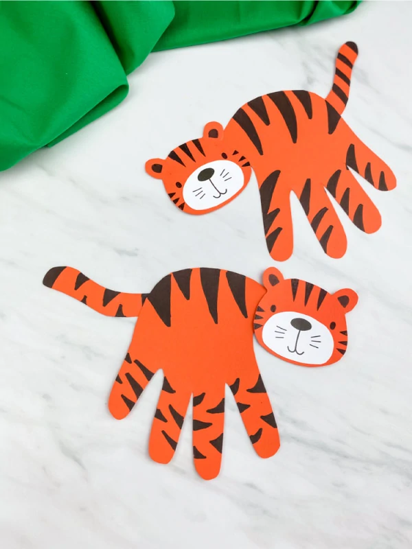 two handprint tiger crafts with green fabric 