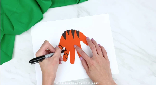 hands coloring in tiger stripes on handprint 
