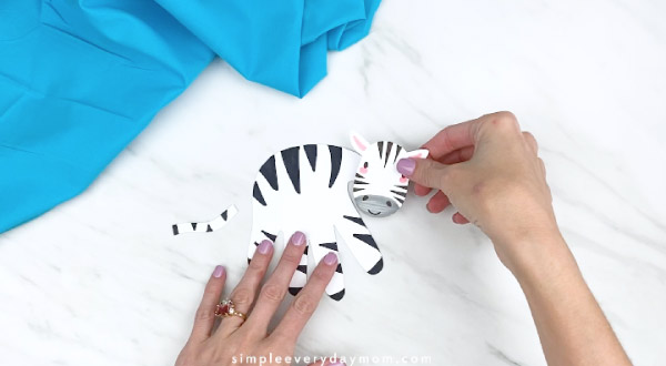 hands gluing on zebra head to handprint zebra 