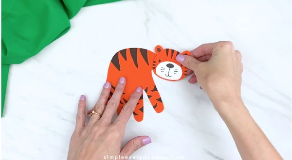 hands gluing tiger head to handprint 