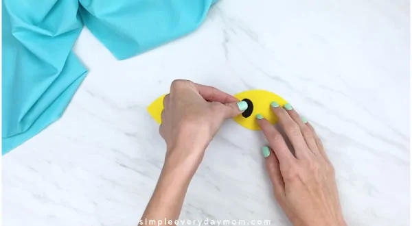 hands gluing pupil to yellow eye 