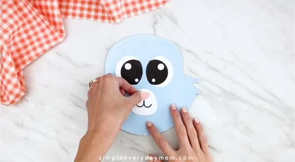 Hands gluing nose onto paper plate rabbit 