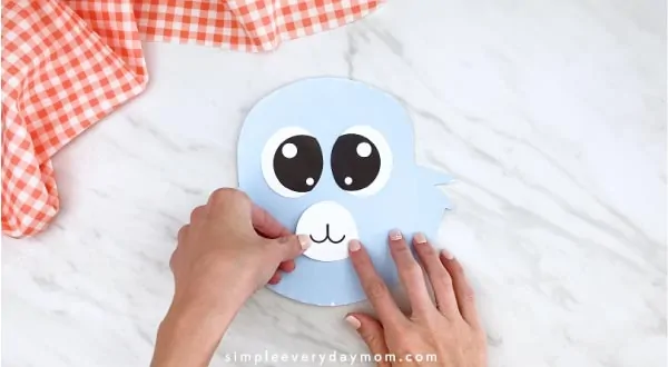 Hands gluing mouth to paper plate rabbit 