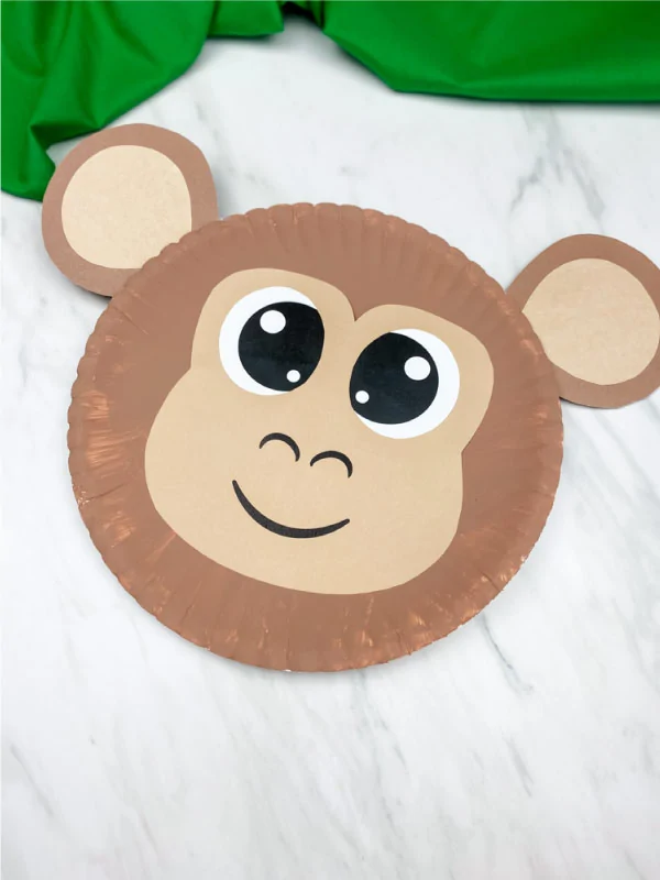 light brown paper plate monkey on marble background with green fabric