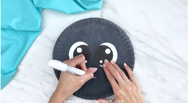 Hand drawing mouth to paper plate sheep 