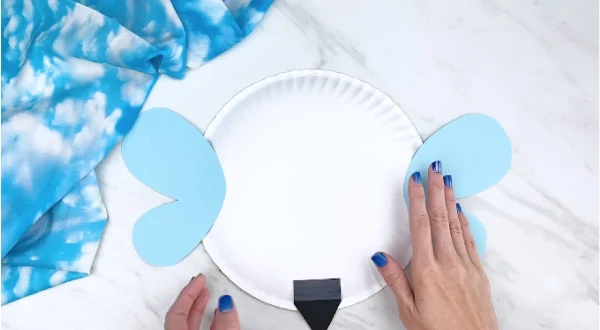 Hands gluing wings to back of paper plate bee 