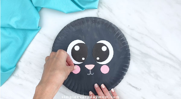 Hand gluing pink cheek to paper plate sheep 