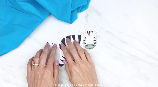 hands gluing on tail to handprint zebra 