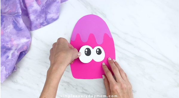 hands gluing on eyes to paper popsicle craft 