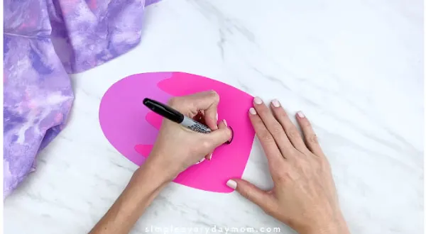 hands drawing smile onto paper popsicle with black sharpie