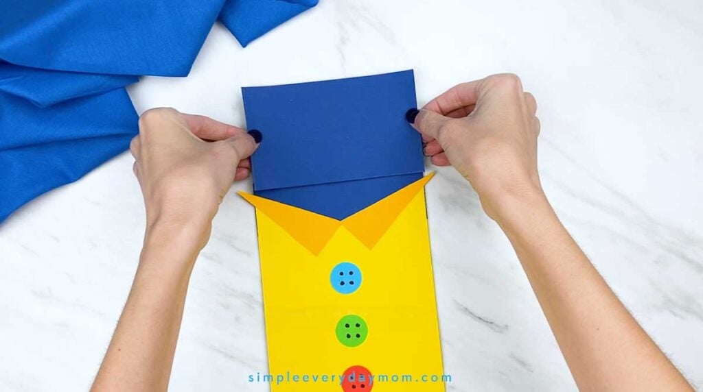 Hands position a dark blue rectangular paper piece over the top of the bag to form Pete the Cat’s head.