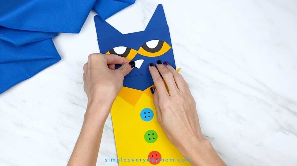 Hands attach a small white triangular nose beneath the eyes on the Pete the Cat puppet.