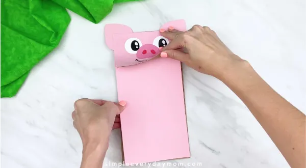 hand gluing pink paper onto paper bag puppet craft 